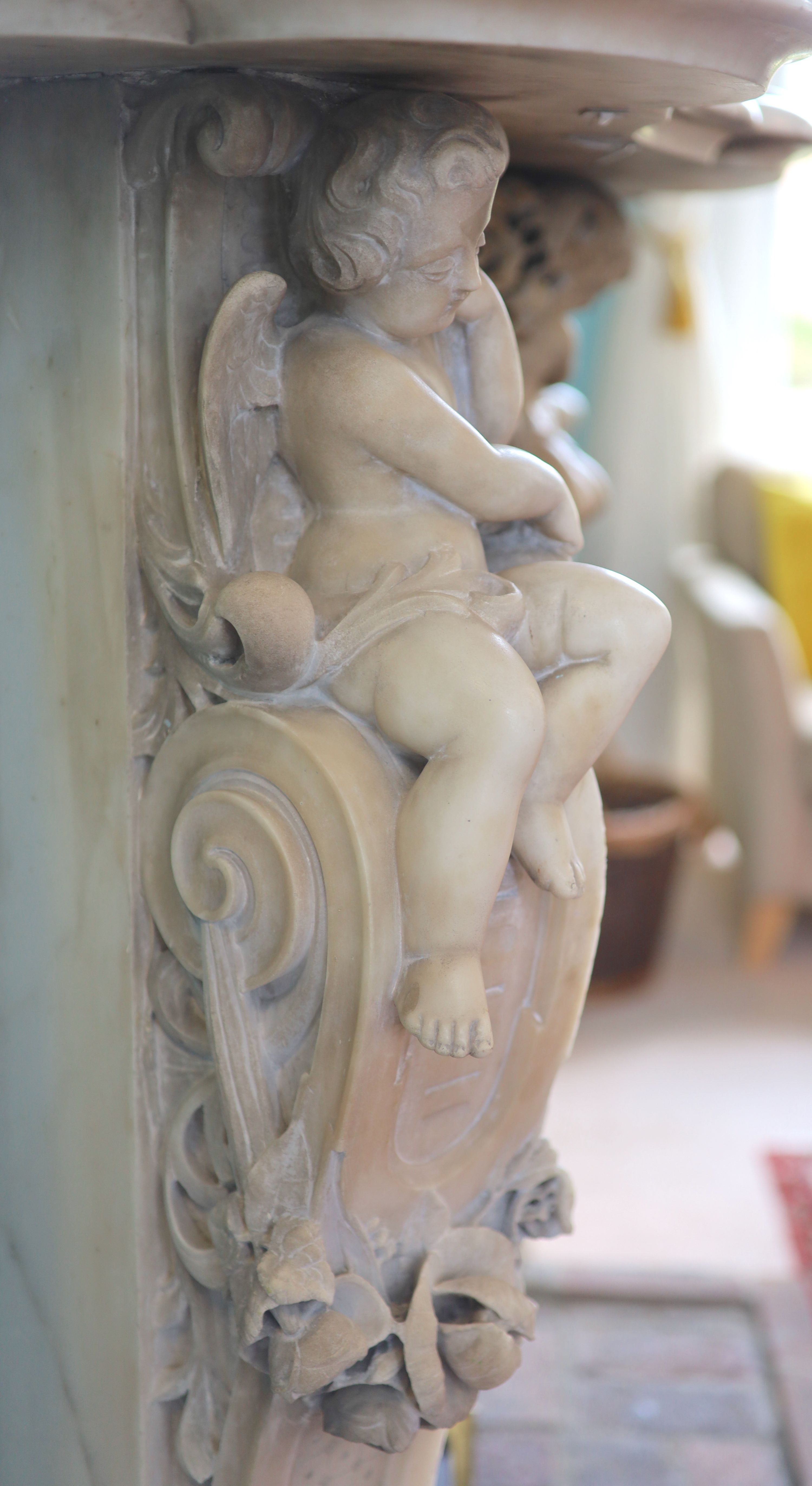 An important mid 19th century Italian white Carrara marble chimney piece, carved in the rococo taste, with seated putti, foliage swags